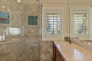 Bathroom with vanity, a shower with door, and a wealth of natural light