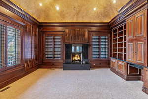 Office with wood walls Imported from Madagascar , light colored carpet, ornamental molding, and built in features