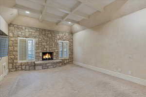 Master Bedroom with beam ceiling, a stone fireplace, light colored carpet, and a high ceiling