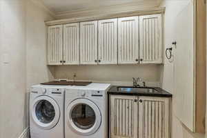 Laundry room featuring separate washer and dryer, sink, cabinets, and ornamental molding