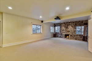 Unfurnished living room with a stone fireplace and carpet floors