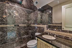 Ensuite  bathroom featuring vanity, toilet, and tile walls