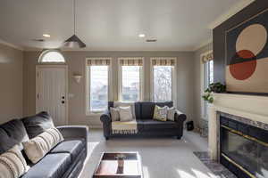 Living room with a premium fireplace, crown molding, and carpet floors