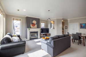 Carpeted living room featuring a tile fireplace and crown molding