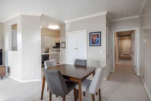 Carpeted dining space with crown molding