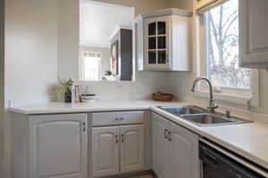 Kitchen with a wealth of natural light, dishwashing machine, sink, and white cabinets