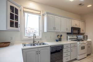 Kitchen featuring white cabinets, sink, light tile patterned flooring, and black appliances