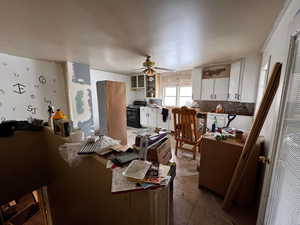 Kitchen with black electric range, white cabinetry, and ceiling fan