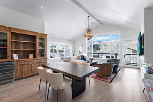 Dining area featuring beamed ceiling, a healthy amount of sunlight, light wood-type flooring, and wine cooler