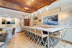 Bar featuring white cabinets, decorative light fixtures, light hardwood / wood-style flooring, and wood ceiling