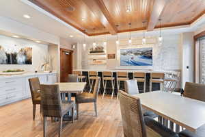 Dining space with light wood-type flooring, a raised ceiling, and wooden ceiling