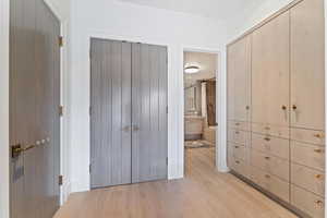 Unfurnished bedroom with ensuite bathroom and light hardwood / wood-style floors