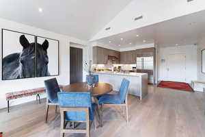 Dining room with sink, high vaulted ceiling, and light hardwood / wood-style floors