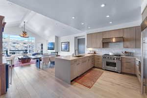 Kitchen with backsplash, stainless steel range, extractor fan, light hardwood / wood-style flooring, and vaulted ceiling with beams