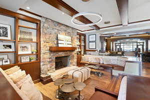 Living room featuring light hardwood / wood-style floors, a stone fireplace, and beam ceiling