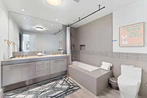 Bathroom with tasteful backsplash, vanity, wood-type flooring, and toilet