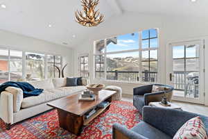 Living room featuring wood-type flooring, lofted ceiling with beams, plenty of natural light, and a notable chandelier