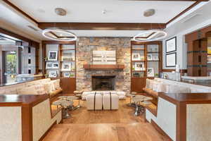 Living room featuring a stone fireplace, light wood-type flooring, and a chandelier