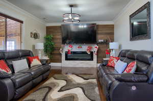 Living room with crown molding, wood-type flooring, wood walls, and an inviting chandelier