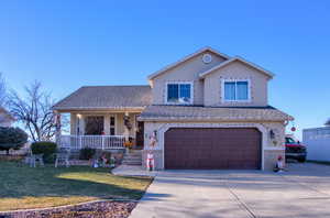 View of front facade featuring covered porch, a garage, and a front yard