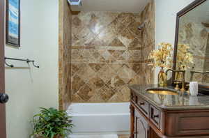 Bathroom with vanity, tiled shower / bath combo, and a textured ceiling