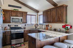 Kitchen with a breakfast bar, sink, appliances with stainless steel finishes, tasteful backsplash, and kitchen peninsula