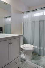 Bathroom featuring a shower with shower curtain, vanity, and toilet