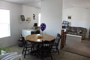 Dining area with carpet floors and vaulted ceiling