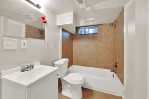 Bathroom featuring vanity, bathing tub / shower combination, tile patterned flooring, and a textured ceiling