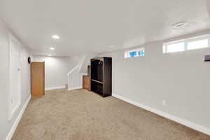 Below grade area featuring recessed lighting, light colored carpet, and stairway