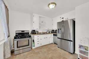 Kitchen featuring white cabinetry, sink, and appliances with stainless steel finishes