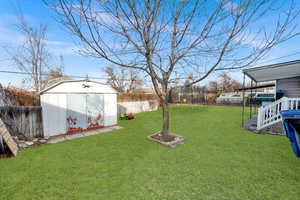 View of yard with a trampoline and a storage shed