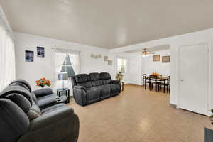 Living room with ceiling fan and light tile patterned floors