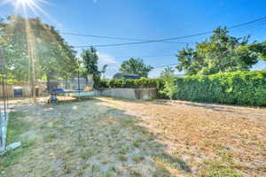 Fenced backyard featuring a trampoline