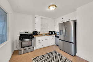 Kitchen with open shelves, stainless steel appliances, white cabinetry, and light countertops