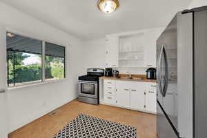 Kitchen featuring appliances with stainless steel finishes, white cabinets, open shelves, and light tile patterned floors