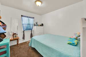 Bedroom featuring dark colored carpet and baseboards