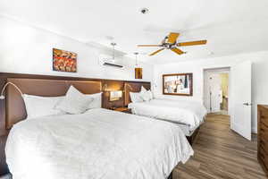 Bedroom featuring ceiling fan, hardwood / wood-style floors, and a wall mounted air conditioner