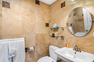 Bathroom featuring toilet, tile walls, and sink