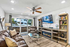 Living room featuring ceiling fan, light hardwood / wood-style floors, and a textured ceiling