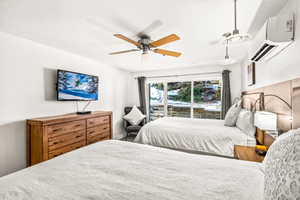 Bedroom with ceiling fan, a textured ceiling, and a wall mounted AC