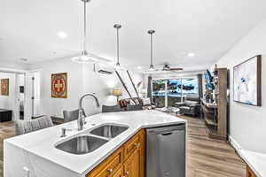 Kitchen featuring dishwasher, sink, hanging light fixtures, light hardwood / wood-style floors, and a wall unit AC