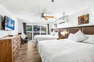 Bedroom featuring ceiling fan, access to exterior, wood-type flooring, and a textured ceiling