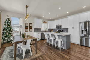 Kitchen featuring white cabinetry, tasteful backsplash, dark hardwood / wood-style floors, decorative light fixtures, and appliances with stainless steel finishes