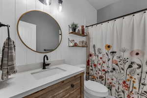 Bathroom featuring wooden walls, vanity, a shower with shower curtain, and toilet