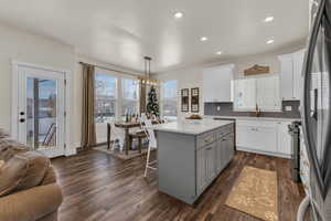 Kitchen with gray cabinetry, hanging light fixtures, dark hardwood / wood-style floors, a kitchen island, and white cabinetry