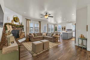 Living room featuring a fireplace, ceiling fan, and dark wood-type flooring