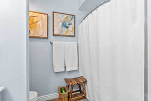 Bathroom featuring hardwood / wood-style floors, toilet, and a shower with shower curtain