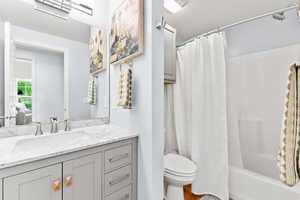 Full bathroom with vanity, toilet, and shower / bathtub combination with curtain