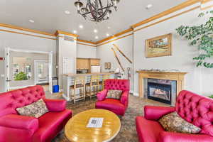 Living room featuring carpet flooring, an inviting chandelier, ornamental molding, and a premium fireplace